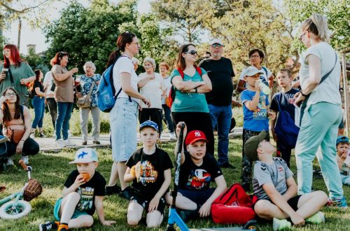 A diverse group of families and children enjoying an outdoor event on a sunny day in a park setting.