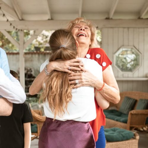 A heartwarming reunion with family members hugging and smiling in a cozy indoor setting.