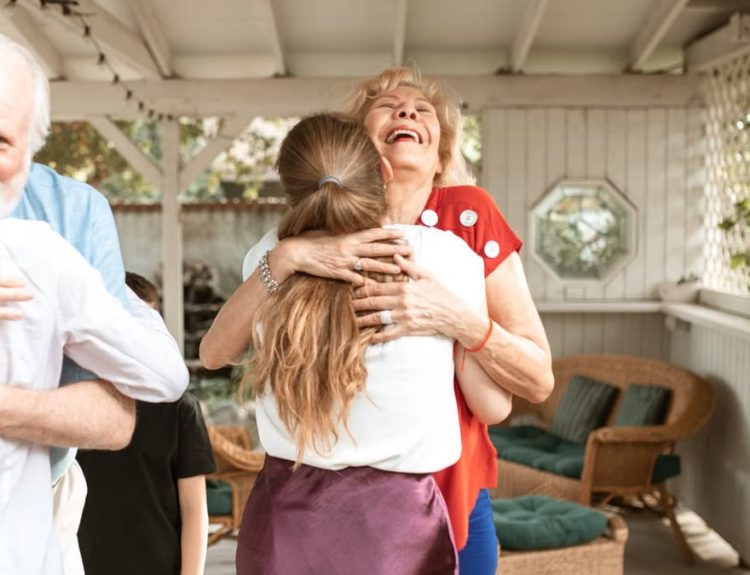 A heartwarming reunion with family members hugging and smiling in a cozy indoor setting.